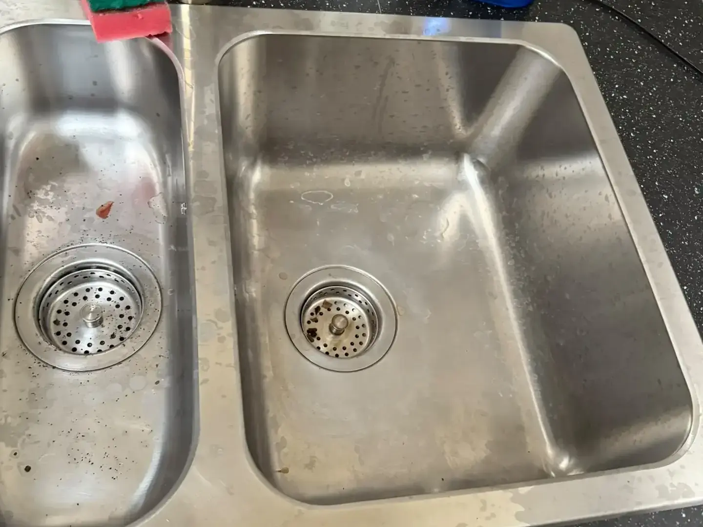 Évier de cuisine avant intervention : traces d'eau sur l'inox et résidus dans la bonde.